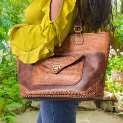 Model displaying brown Kimbia tote bag hanging from her shoulder, made from Argentinian leather featuring an exterior pocket and two straps. Made by Gy Crafts.
