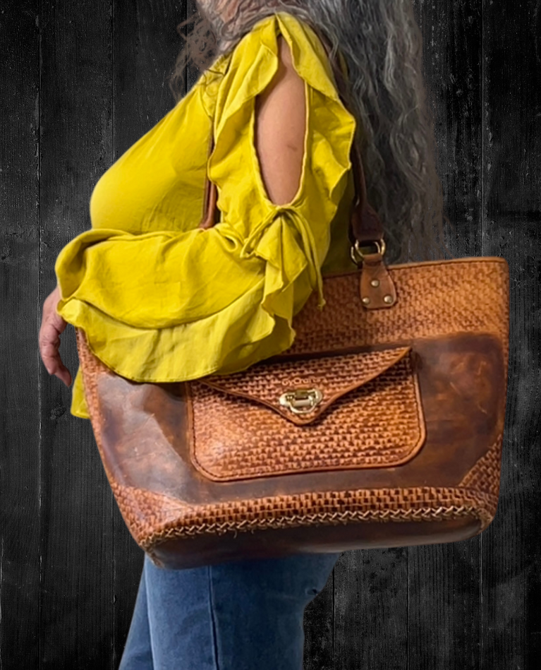 Model displaying brown kimbia bag hanging from her shoulder featuring outer pocket with flap closure. Made by Gy Crafts