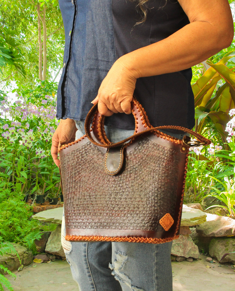 Model displaying brown Puruni wristlet hanging from her hand closer to her wrist. Made by Gy Crafts.