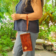 Model displaying Brown Puruni wristlet hanging by the strap on her arm close to her wrist. This wristlet is made from aged Italian Tuscany leather with a single strap and zip closure. Made by Gy Crafts.