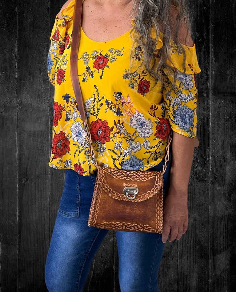 Model displaying brown Wonotobo bag featuring a single strap across her body and has a flap closure. Made by Gy Crafts.