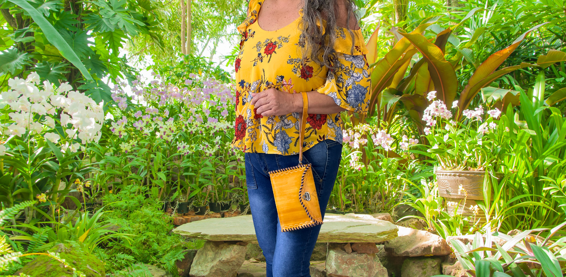 Model displaying yellow Ituni wristlet hanging from her hand closer to her wrist. Bag has a flap closure