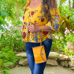 Model displaying a yellow and purple Ituni wristlet hanging from a single strap on her hand closer to her wrist. Made by Gy Crafts.